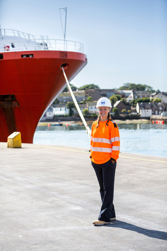 woman standing quayside at Montrose Port with hard hat and high vis.