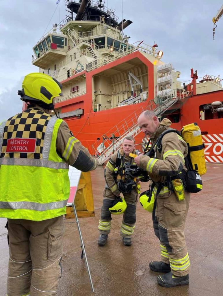 Crew from the Scottish Fire and Rescue Service putting on their fire safety gear on the quayside next to the Atlantic Kestrel vessel at Montrose Port Authority