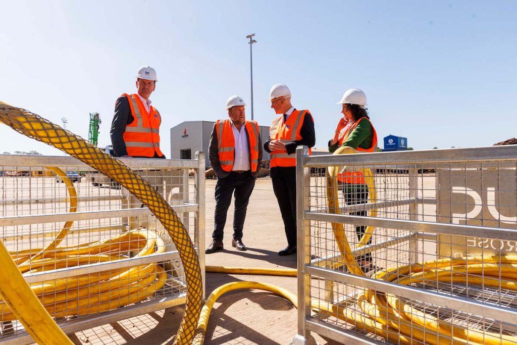 Dave Doogan MP, Montrose Port CEO Tom Hutchison, First Minister John Swinney and Mairi Gougeon MSP, all wearing high-vis and hard hats standing behind shore power cabling on the Montrose Port South Quay.