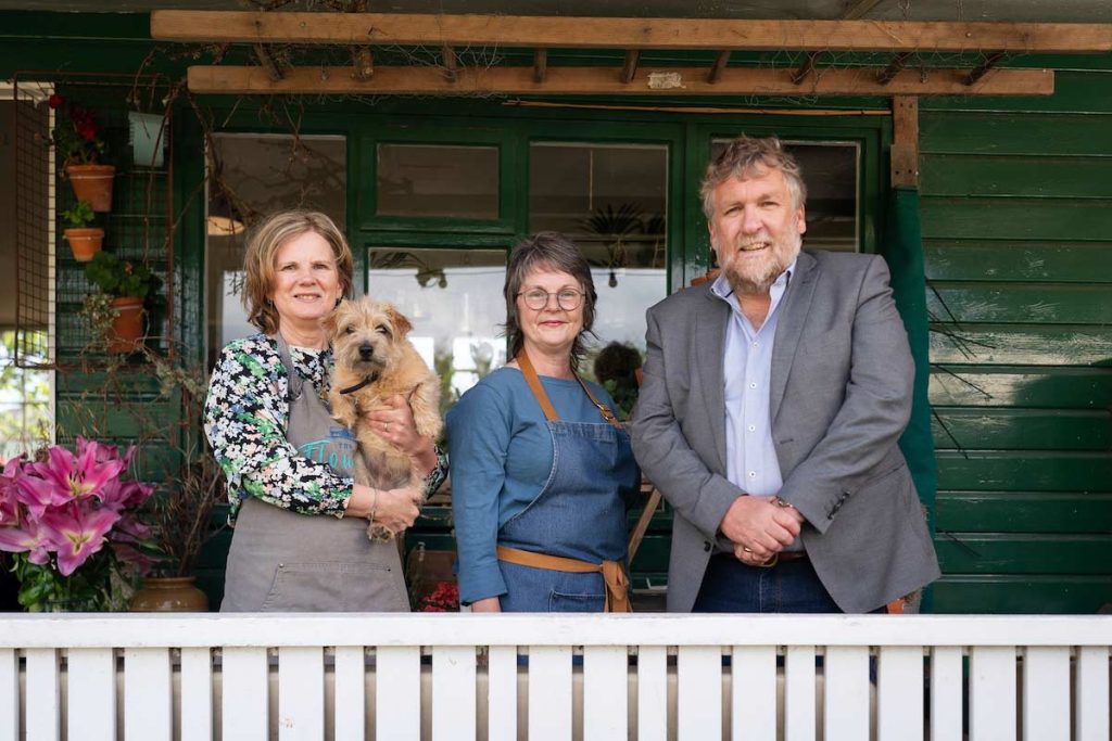 The Flower Pavilion owner, Linda Cooper, holding her dog Liesel and standing next to Donna Grove-White, owner of Roamer Coffee Company and Tom Hutchison, CEO of Montrose Port.