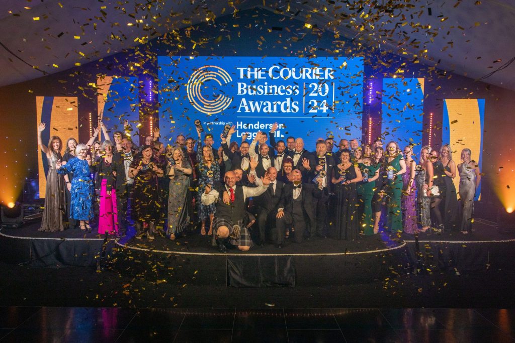 All the winners of The Courier Business Awards standing on stage with golden confetti around them. 